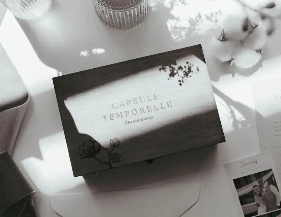 Coffret en bois gravé Capsule temporelle Chronobooth, posé sur une table à côté d'une photo des mariés